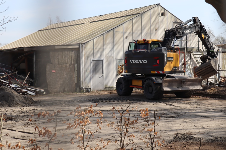 Old greenhouse with an excavator in front