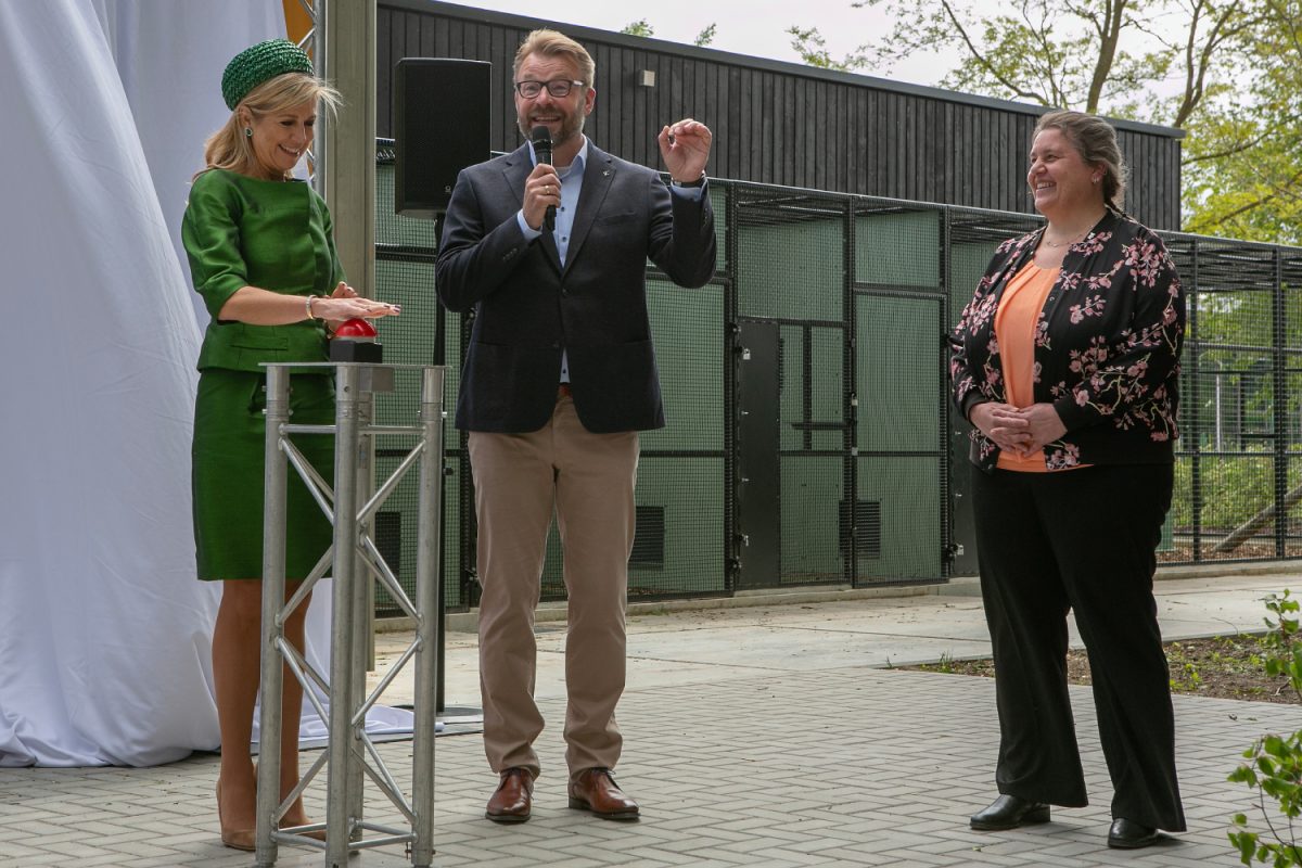 Three people standing beside a pole with a button
