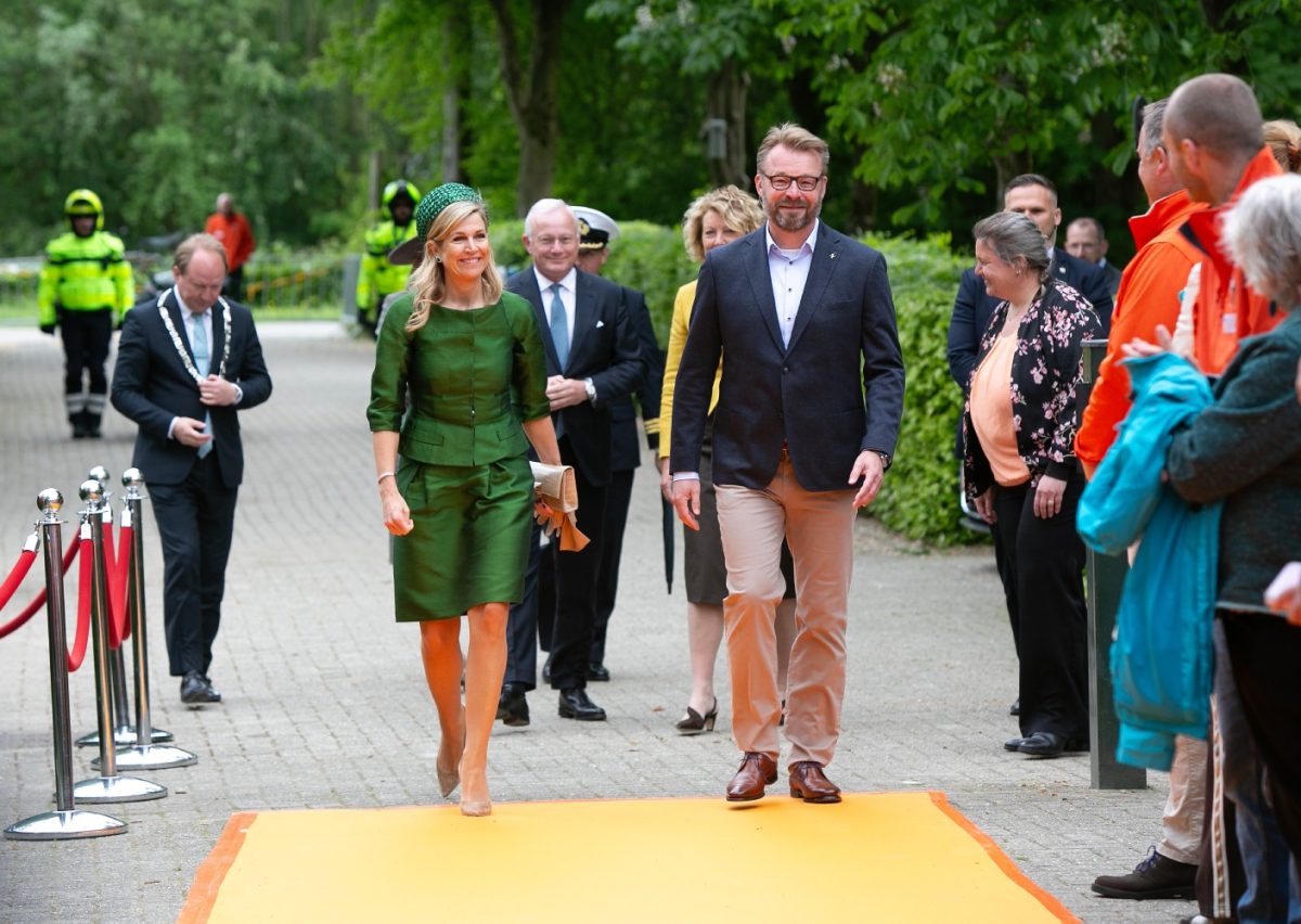 Two people walking on an orange carpet.